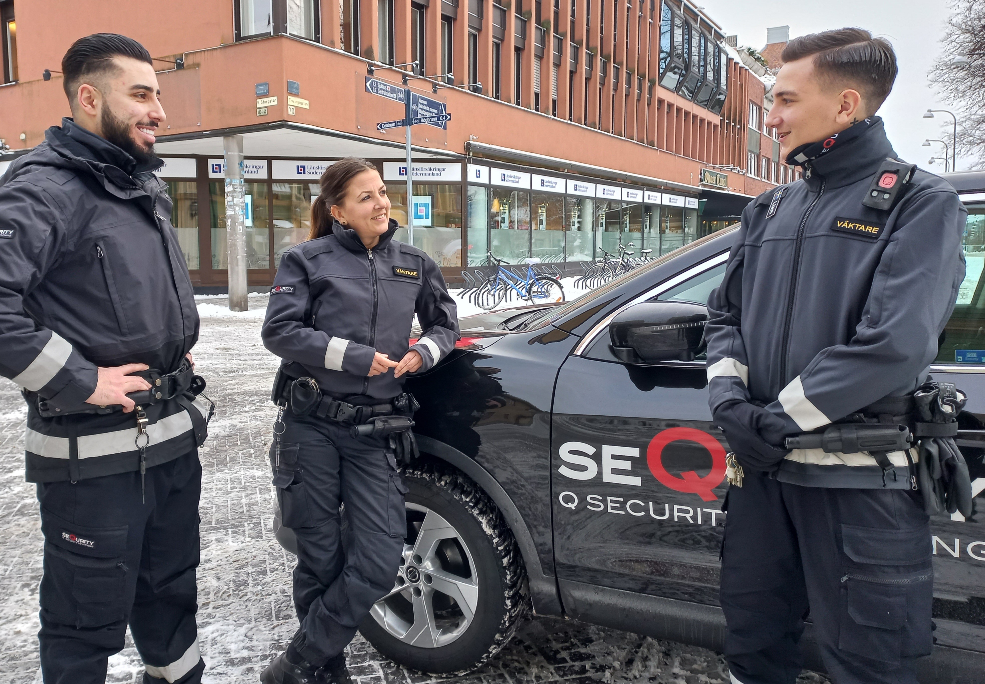 Tre väktare vid en väktarbil.