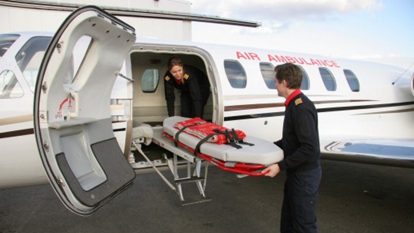 Två personer som tar ut en bår ur Cessna Citation II