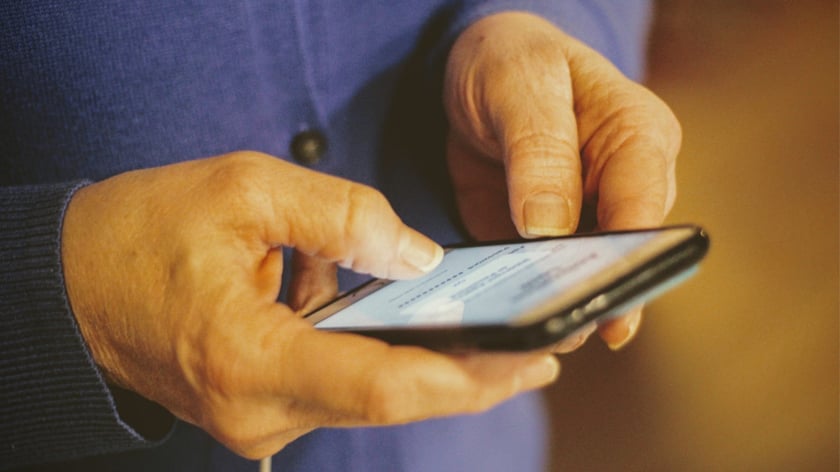 Närbild på händer som håller i en telefon och knappar på den