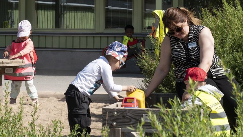 Två barn och en pedagog som gräver i ett land på en förskolegård Två barn och en pedagog som gräver i ett land på en förskolegård
