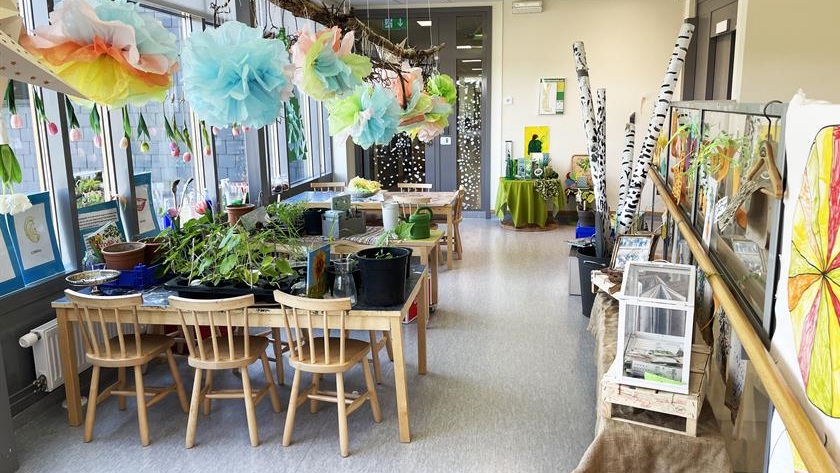 Inomhusmiljö på Svalsta förskola med bord och stola, växter på borden, pappersblommor hänger ned från taket
