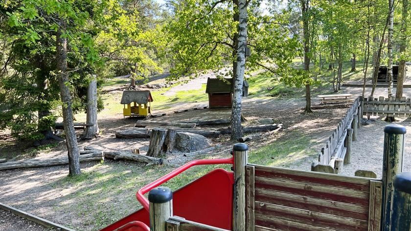 Gården på förskolan med rutschkana i förgrunden och små hus och skog