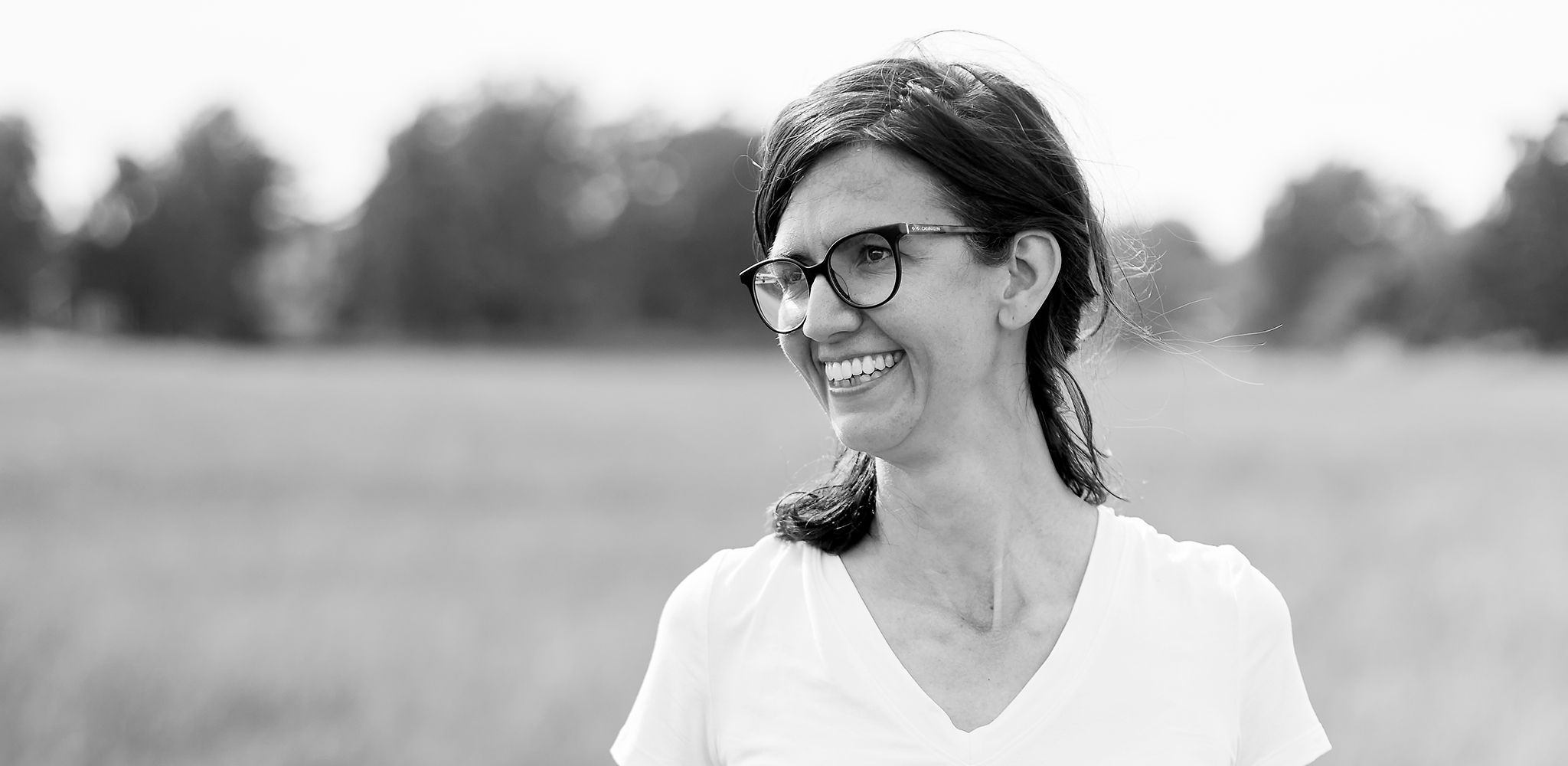 Annika tittar ut mot en åker och ler